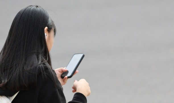 초등학생 자녀 위치 확인 - 부모가 스마트폰으로 자녀 위치를 확인하는 모습